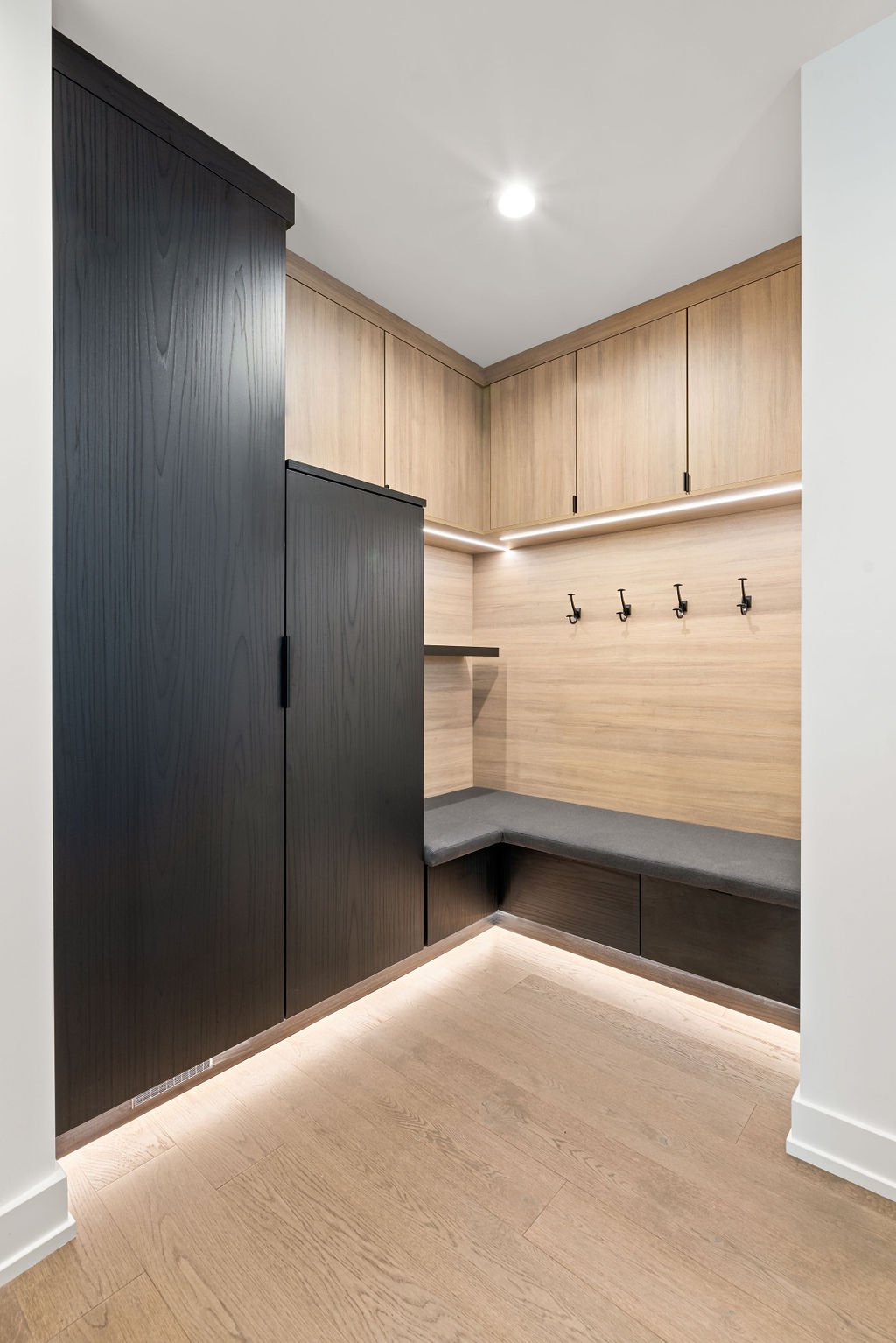 Detroit Loft Mudroom Virtuso Mudroom with black and brown color boards, hooks, and a black bench
