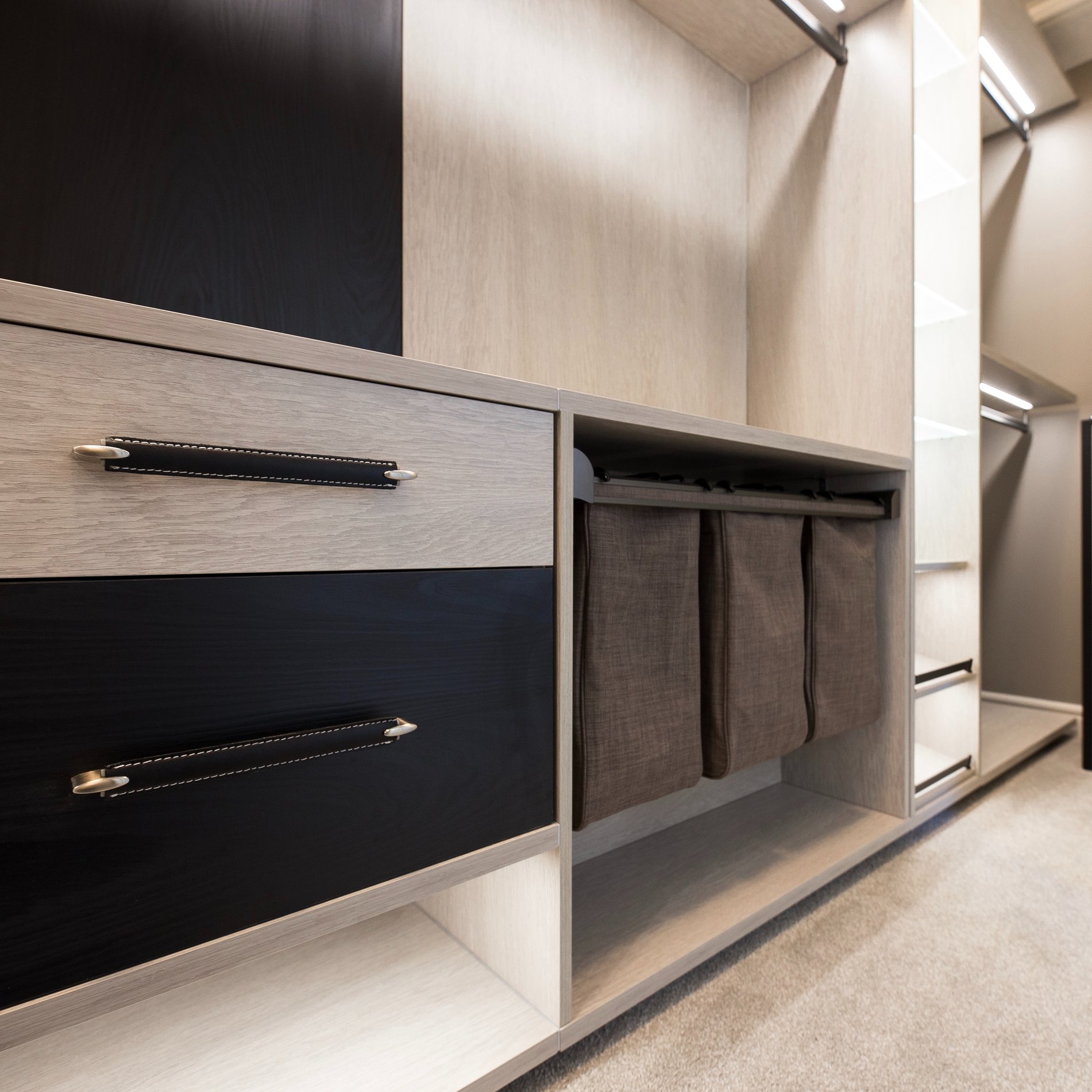 Modern and Moody Walk In Closet Modern walk in closet with contrasting light and dark finishes, lighting, and pull out laundry baskets.