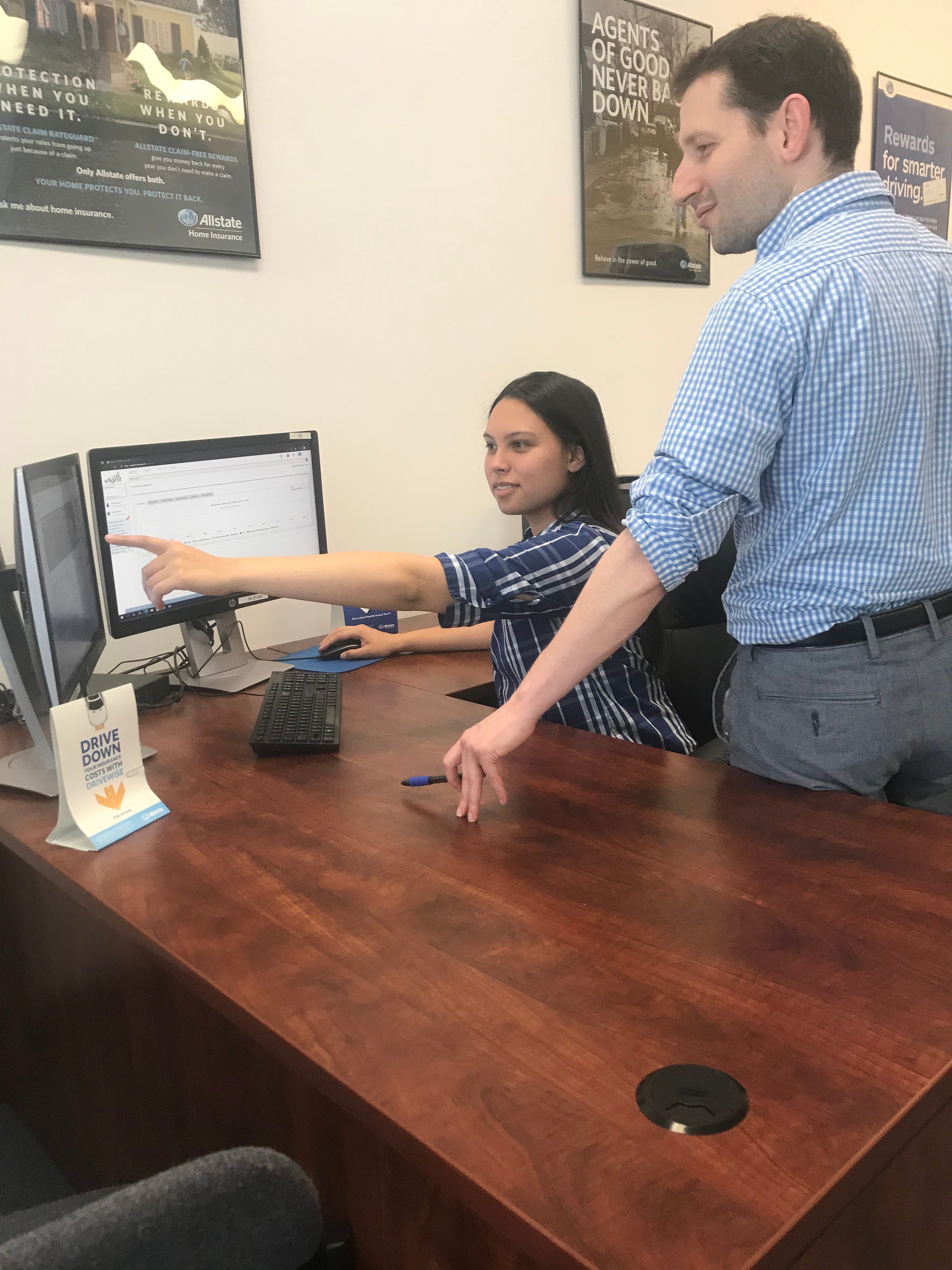 Administrative Assistant Cheyenne Petzold points out to Licensed Insurance Rep. Robert Grossman a recently announced Auto Insurance rate reduction.