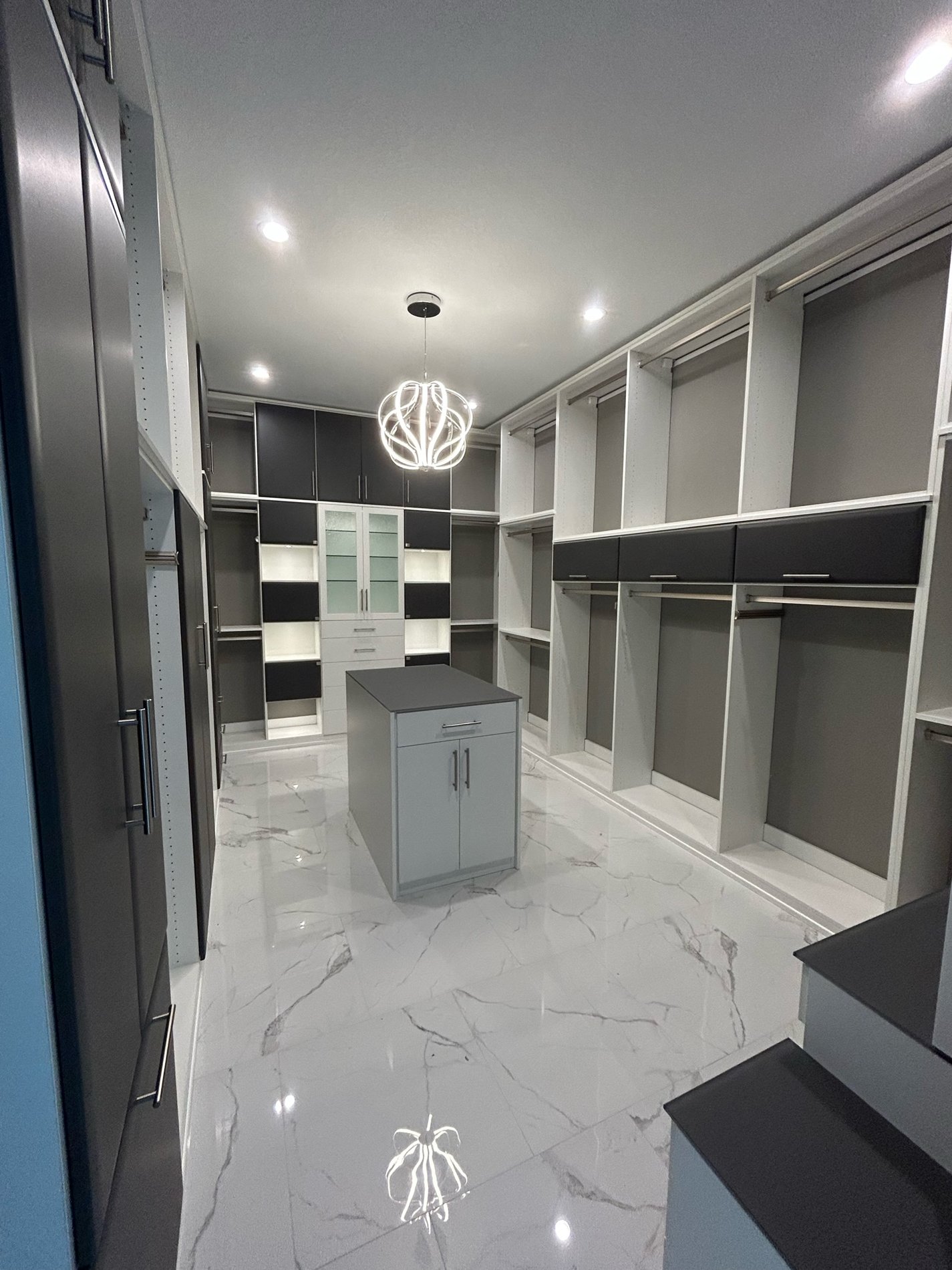 Elegant Walk-In Closet with Island & Vanity in Dove with Supermattes, Rain Glass, & LED Lighting WALK IN CLOSET with an ISLAND and a VANITY in DOVE with SUPERMATTE FRONTs, SQUARE MITER with RAIN GLASS and GLASS COUNTERTOPS and LED lighting