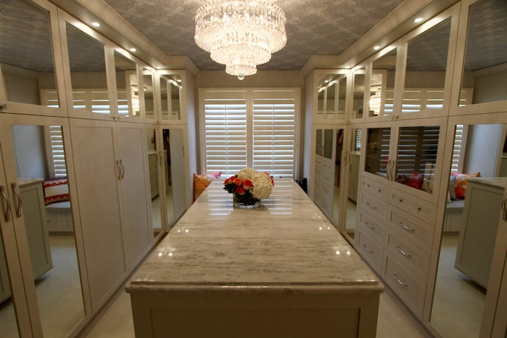 Award-Winning Walk-In Luxury, custom walk-in closet with quartz countertop island, mirrored doors, floor-to-ceiling trim with puck lighting throughout.