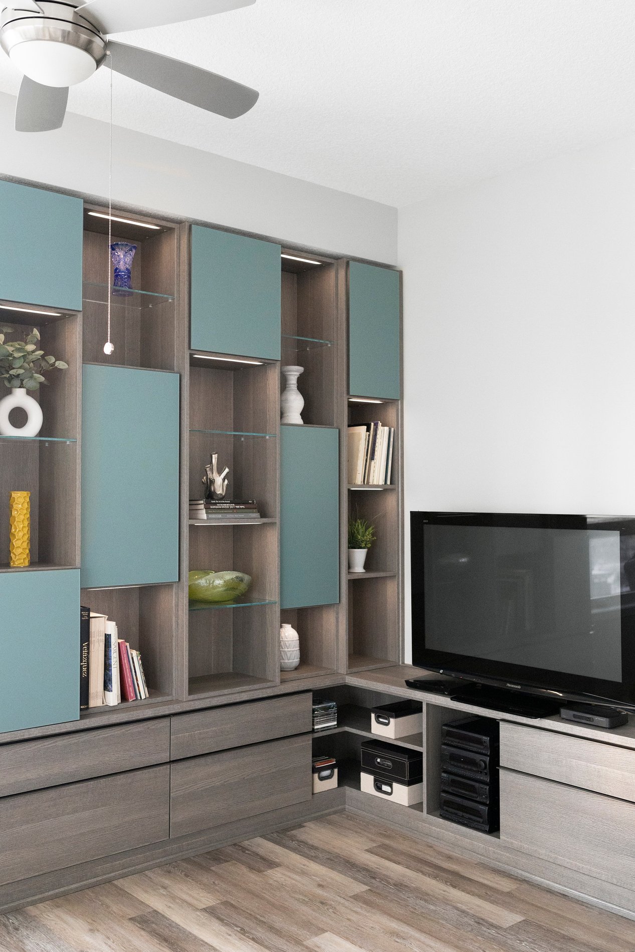 Transitional Media Centre Transitional media design with open cubbies, blue glass doors, and lower drawers.