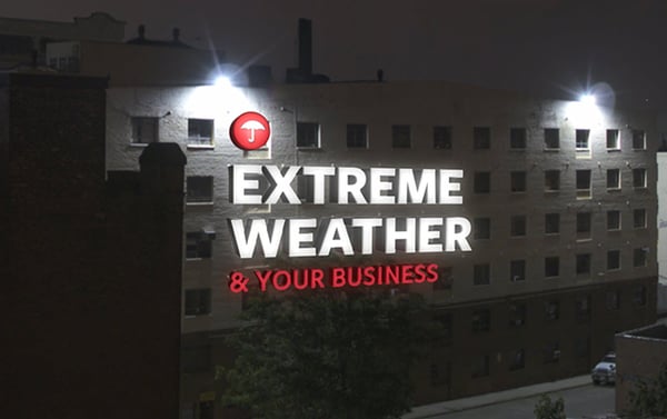 A night image with text across a building stating "Extreme Weather and your business"
