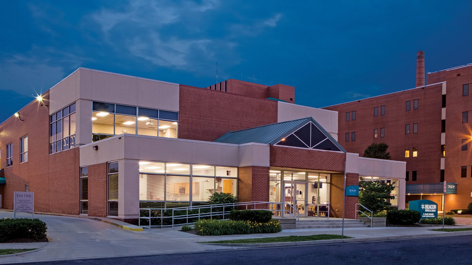 The entrance to Beacon Medical Group East Blair Warner, with lights inside shining into the night.