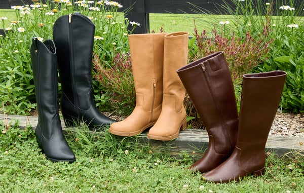 Three pairs of boots are displayed in the grass