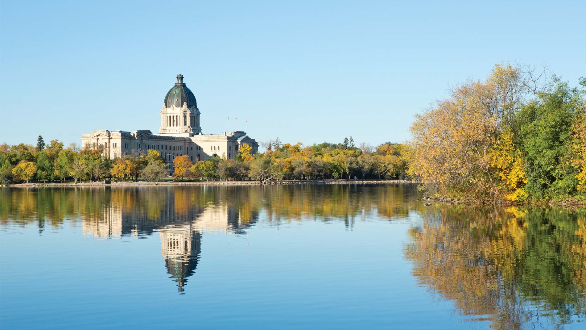 The Saskatchewan Legislative Building is reflected in Wascana Lake on a beautiful, sunny autumn morning in Regina, Saskatchewan