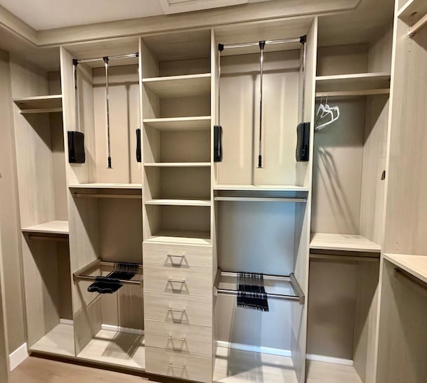 Custom Walk-In Closet with Accessible Storage Solutions Custom walk in closet featuring built-in closet systems, adjustable shelving, pull-down hanging rods, drawers, and closet organization solutions designed to maximize storage and accessibility. Williamsburg, Michigan