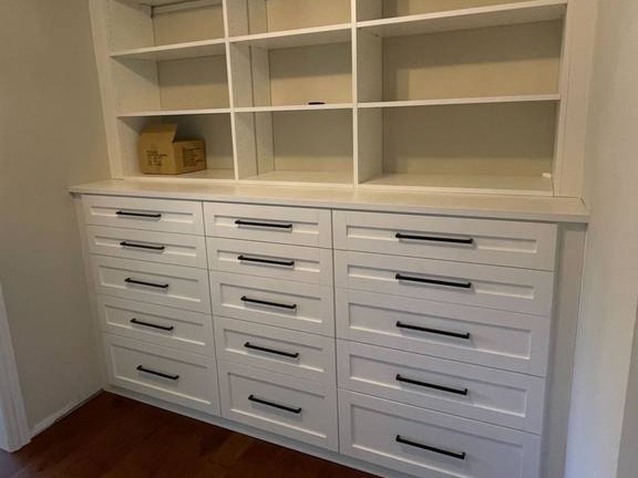 Built-In Wall Storage with Shelves and Drawers A built-in wall featuring shelves and drawers for organized storage.