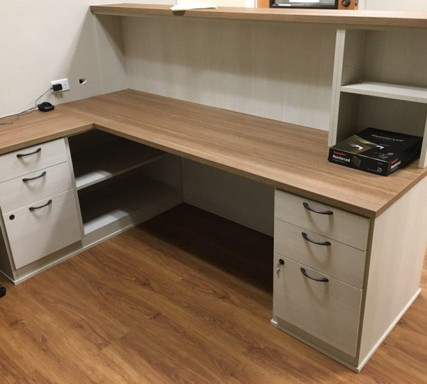 Warm & Welcoming Receptionist Desk Light colored receptionist desk with light brown countertops, open shelving and file drawers with locks.