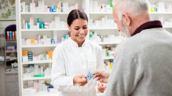 Pharmacist smiling as she hands a customer some medicine