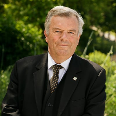 A male Funeral Director with cropped hair and a black suit smiles gently to camera