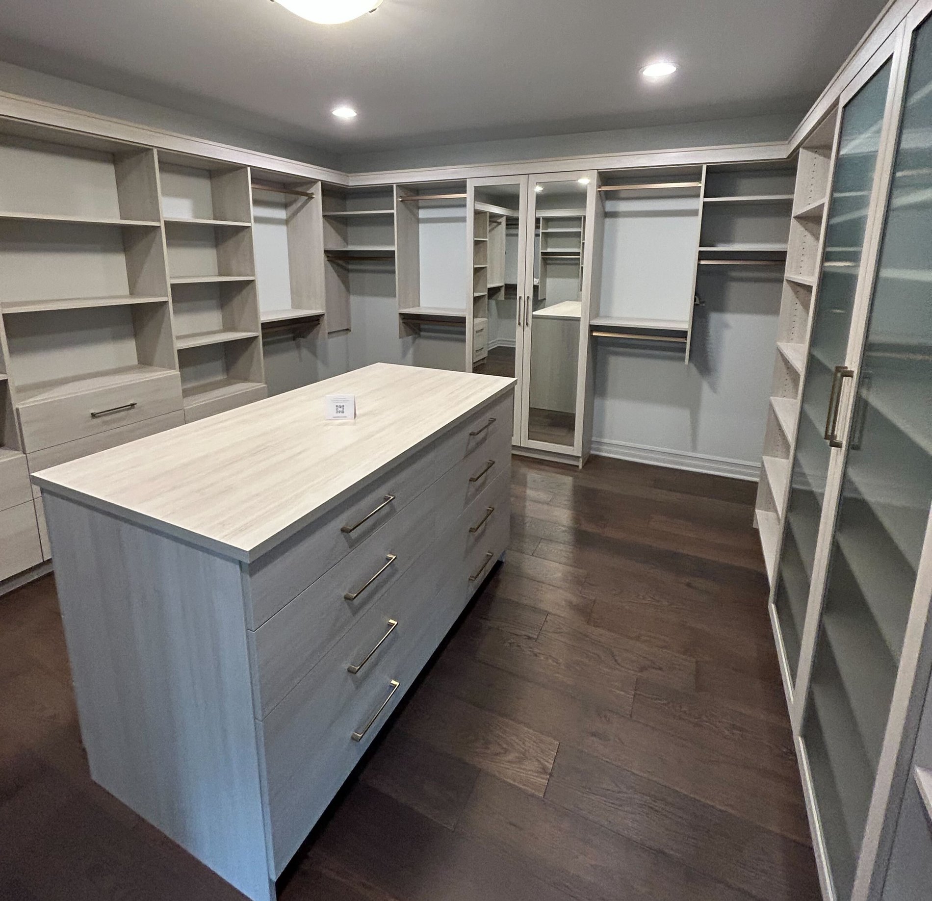 Custom Walk In Closet Walk in closet with Glass doors, hanging space, and an Island
