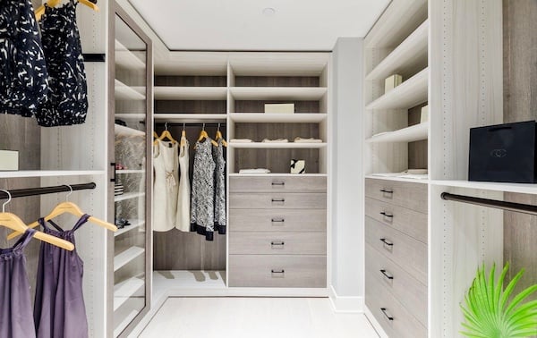 Custom Walk-in Luxury walk-in closet featuring custom closet organization with open shelving, built-in drawers, hanging storage, and glass-front cabinetry in a light wood finish. This custom closet system by California Closets creates elevated bedroom storage with personalized organization solutions and modern home organization design.