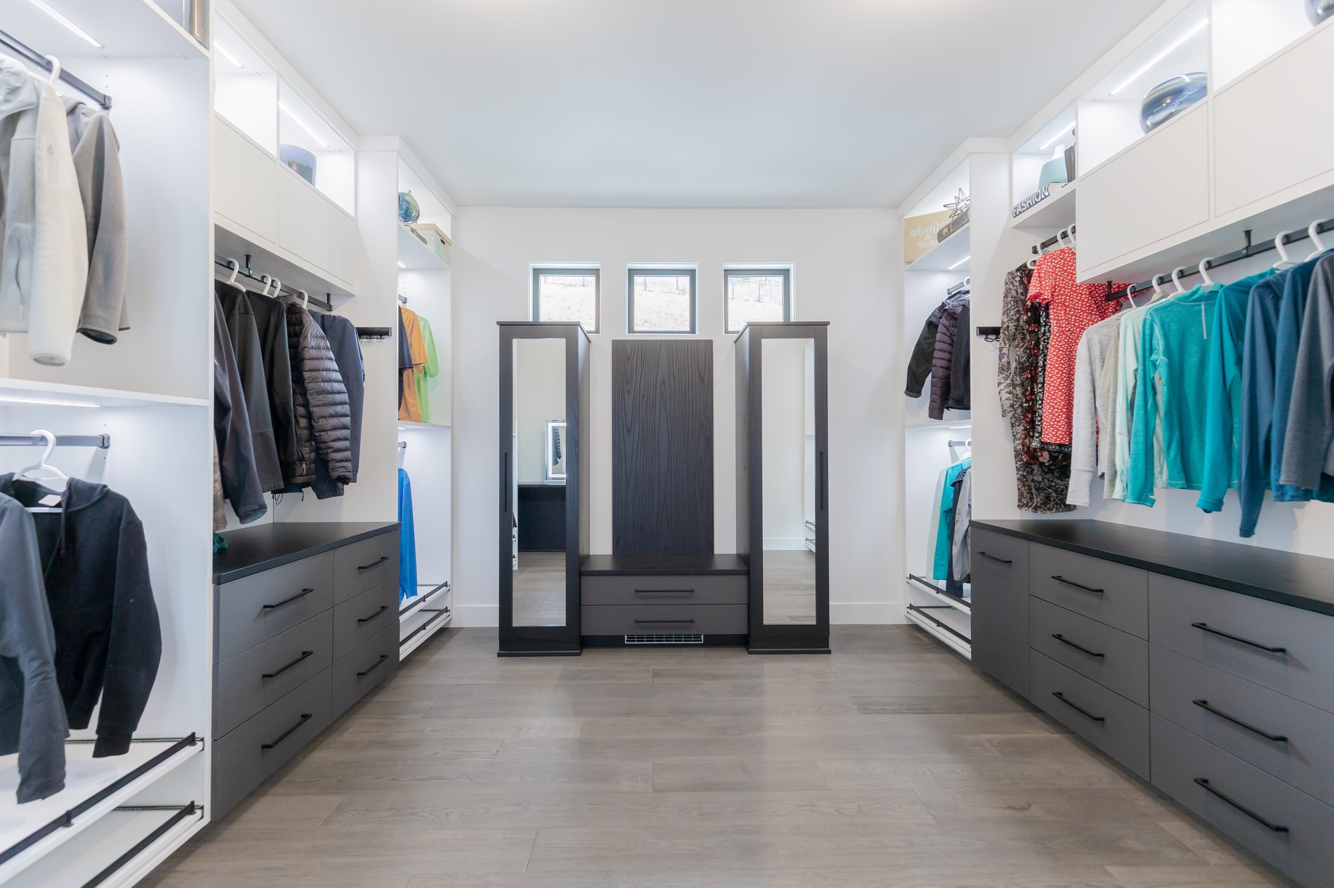 Dark grey closet shelving with organized clothes and built-in lighting