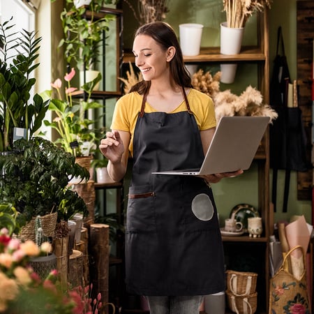 A woman holding a laptop in a garden store.