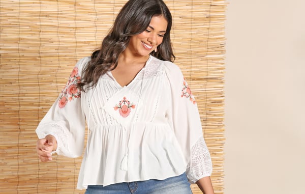 Woman is wearing a plus size white long sleeve blouse.