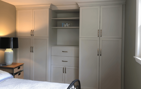 Custom Wardrobe with floor-to-ceiling storage Light toned wardrobe with floor to ceiling cabinets and center dresser with shelves above.