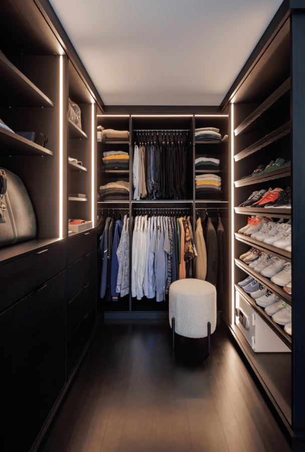 His Primary Walk-in Closet Dark wood primary walk-in closet with lighting