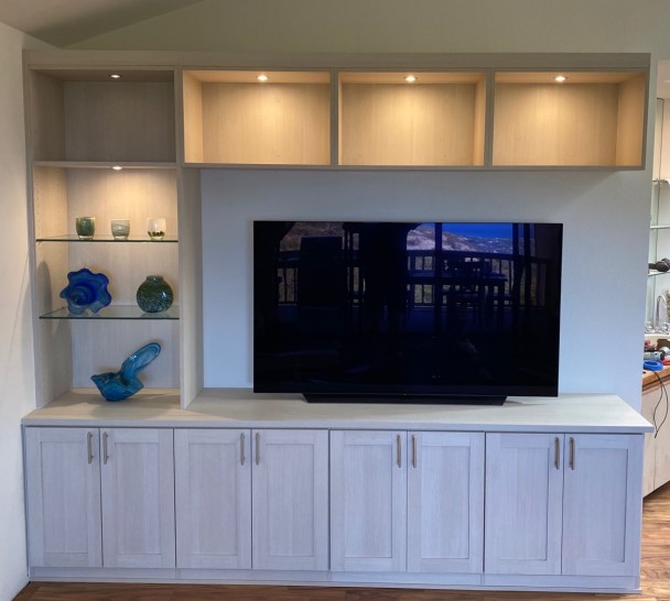 Contemporary Media Center Asymmetrical media center in light finish with glass doors on upper cabinets, glass shelving and recessed lighting.