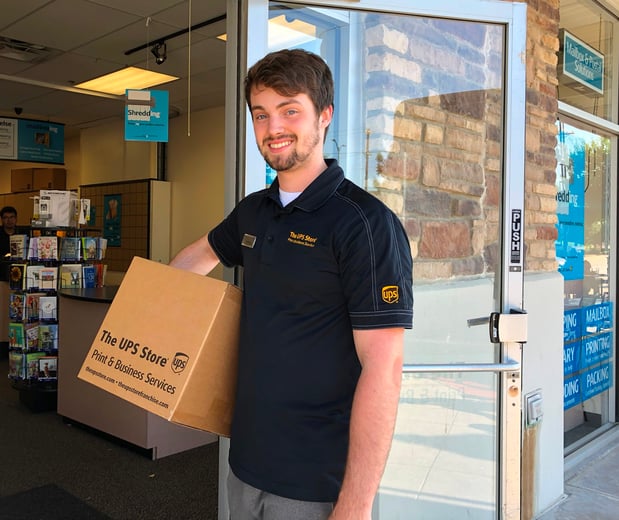 The UPS Store associate carrying a box in front of a The UPS Store