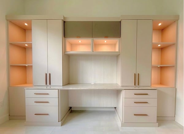 This custom home office by California Closets South Palm Beach features a built-in desk surrounded by floor-to-ceiling cabinetry, overhead storage, integrated lighting, open display shelving, file drawers, and custom organization solutions. Designed to maximize storage while creating a functional and elegant workspace, this custom office blends timeless design with everyday productivity for homeowners in South Palm Beach, Florida. Designed by Wendy Kis. Custom home office by California Closets South Palm Beach featuring a built-in desk with custom cabinetry, illuminated display shelving, overhead storage cabinets, file drawers, and a spacious workspace. Designed for organization and productivity in South Palm Beach, Florida.