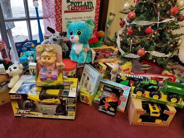 A large pile of Christmas gifts sit under a tree