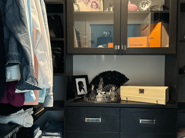 Every pair of shoes should have its place in the closet. Walk-in closet design with black glass door cabinets, shelving, drawers and hanging rods by California Closets Myrtle Beach, South Carolina.