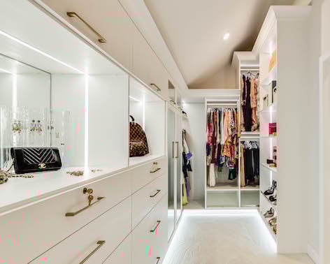Luxury Walk-In for Her x Toll Brothers Her walk-in closet with lighting and white doors and cabinets.