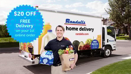 Delivery driver standing in front of Randalls delivery truck holding groceries.