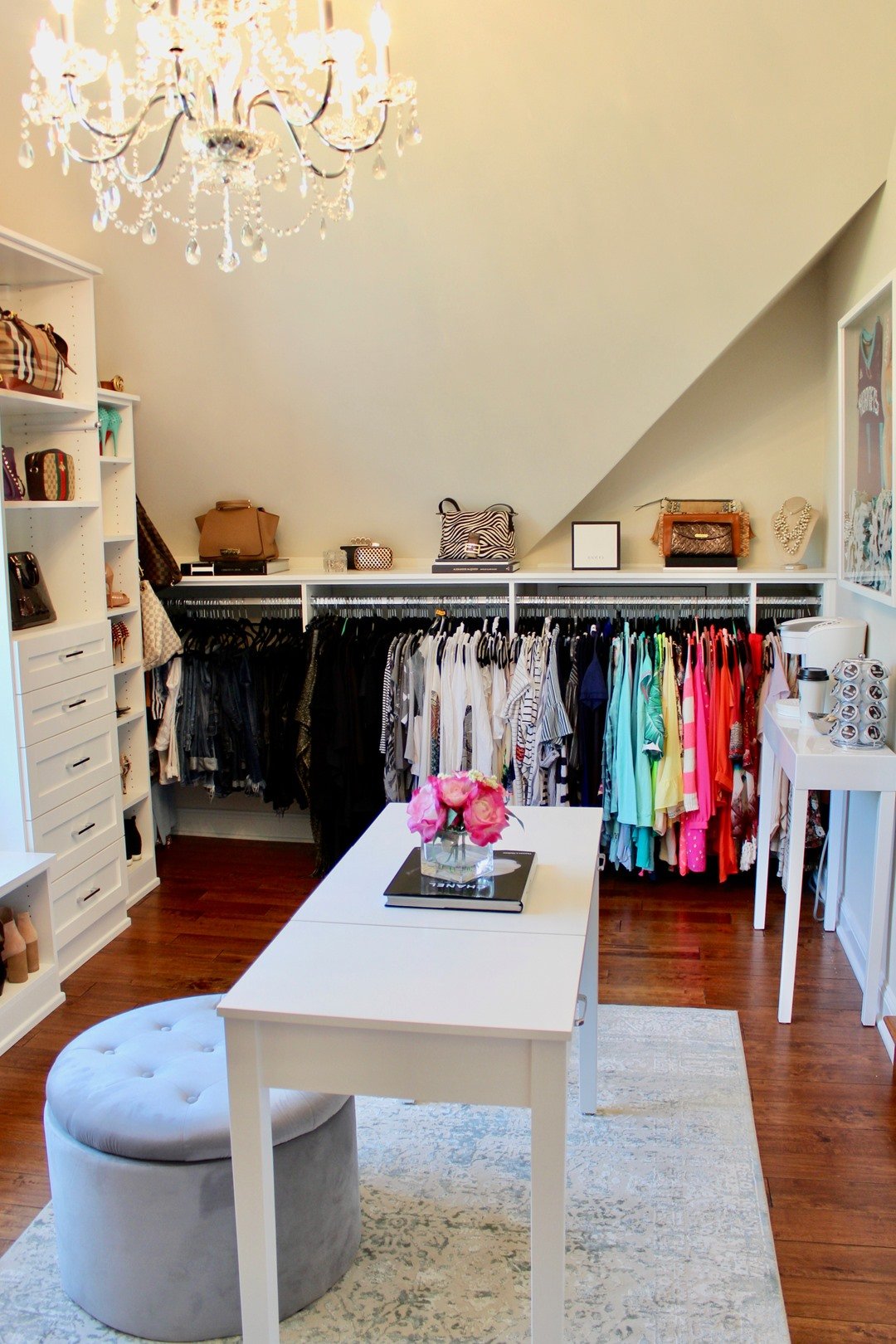 Color Coordinated White closet with short low hanging, color coded blouses, vanity and chandelier by California Closets Kansas City, KS.