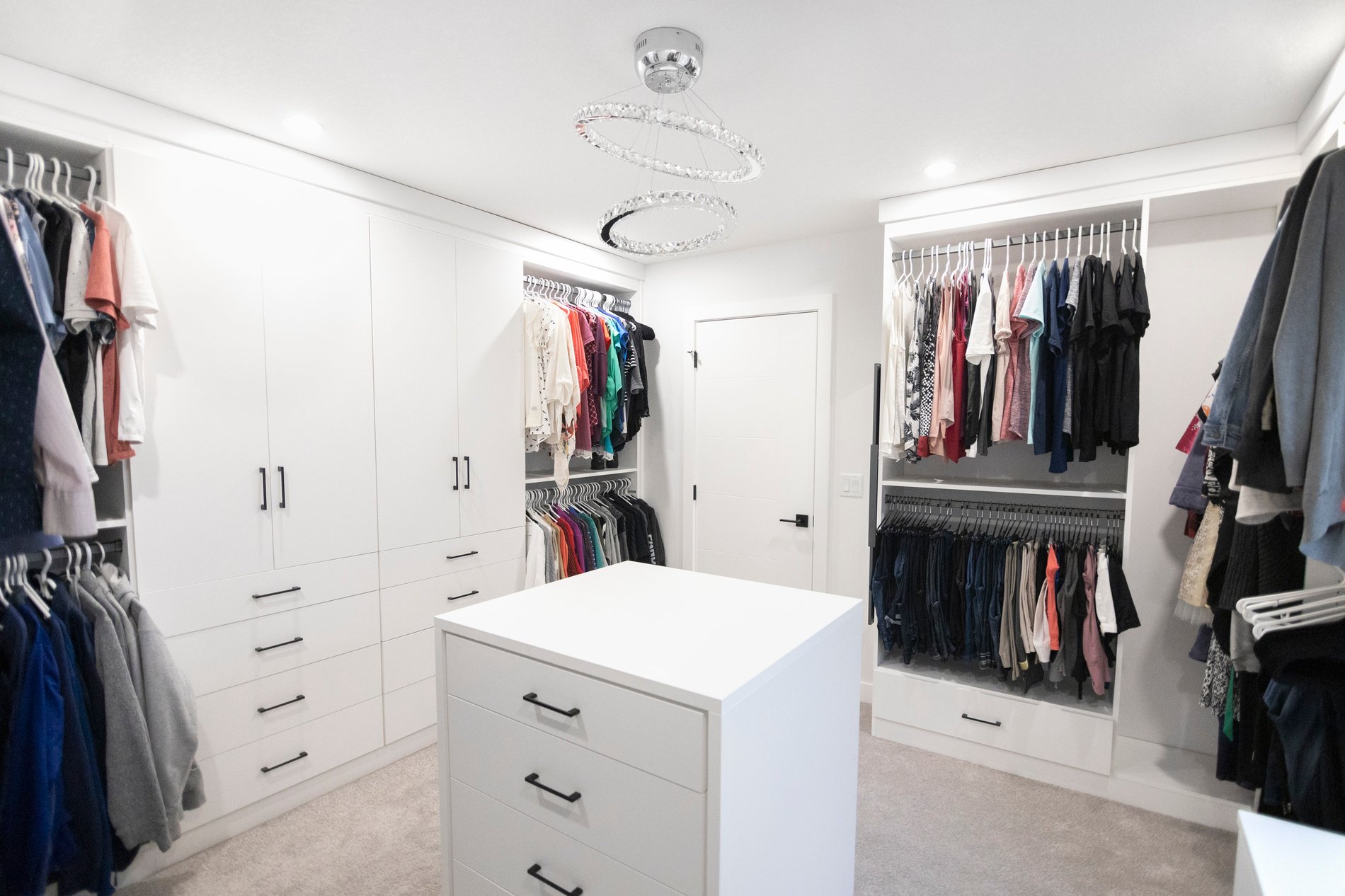 Simple and Elegant Walk In Closet White walk in closet with floor to ceiling storage. Closed cabinetry and island provides plenty of concealed storage. Add black hardware for a contrasting element.
