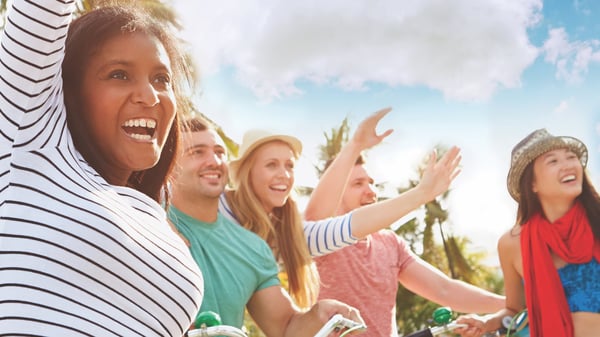 A group of young people cheer under a blue sky.