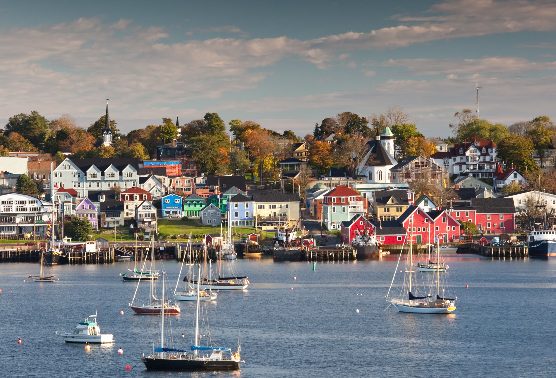 Boats drift in a harbour with a historic town in the background.