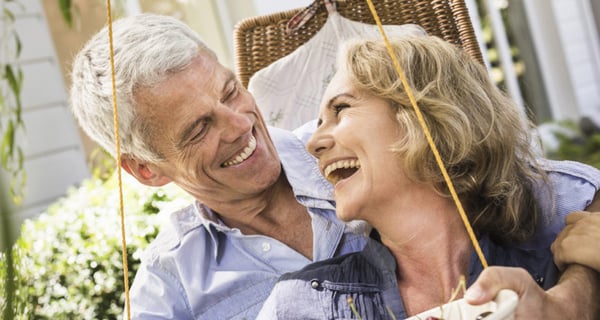 Man smiling while looking at wife as they sit together outside