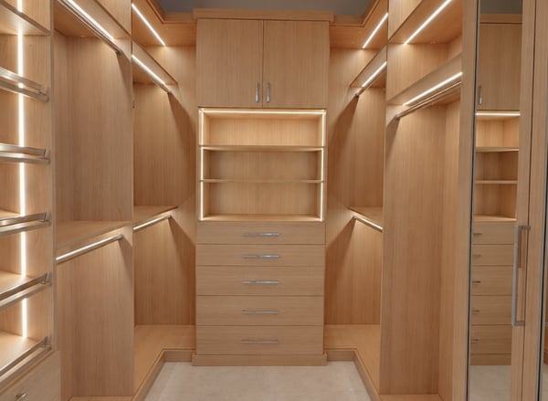 Luxury custom walk-in gallery closet by California Closets South Palm Beach, designed by Wendy Kis. This elegant space features warm wood finishes, integrated LED lighting, glass-front cabinetry, custom drawers, and beautifully organized built-in storage. Custom luxury walk-in gallery closet by California Closets South Palm Beach featuring glass-front cabinetry, integrated LED lighting, custom drawers, and built-in storage. Designed by Wendy Kis.