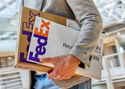 Customer holding FedEx shipping boxes and a mailer ready for packing and shipping