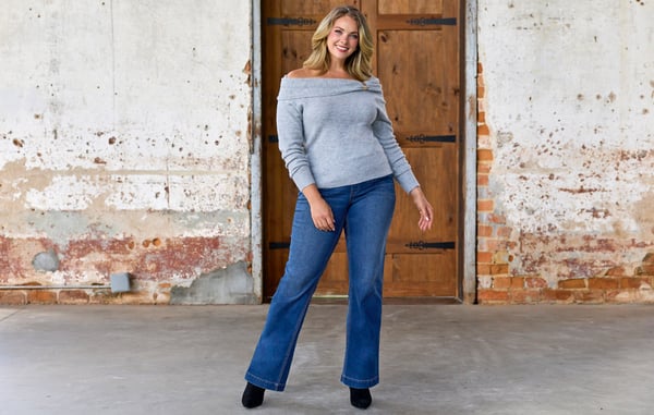 Woman is wearing plus size bootcut jeans and a gray sweater.