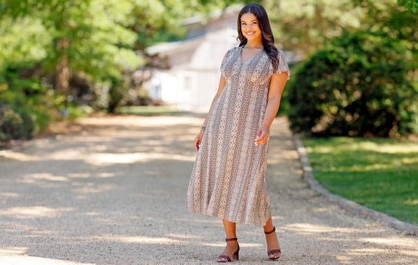 Woman is wearing a plus size midi dress from Cato Fashions.