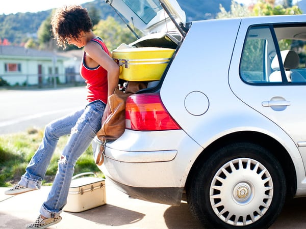 girl packing suitcases into a car