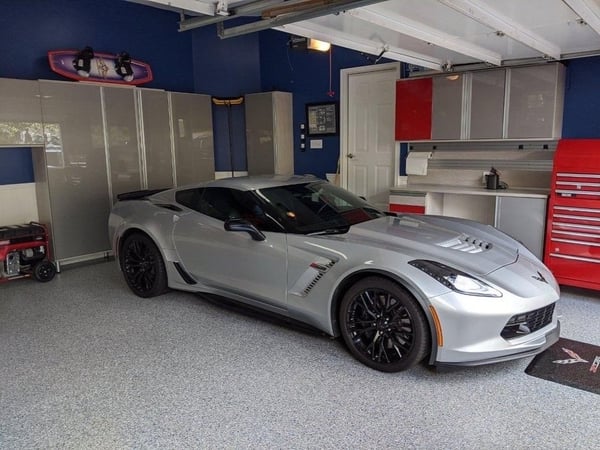 A polished garage designed to complement an impressive car collection, with custom cabinetry, wall storage, work surfaces, and overhead organization that keeps the space streamlined and functional. Luxury custom garage with built-in cabinetry, overhead storage, wall organization, work surfaces, and sports car.
