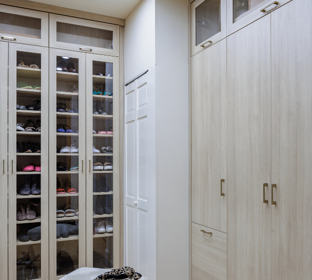 Sleek Walk-in Closet Natural wood walk-in closet with custom cabinetry by California Closets Nassau County, New York