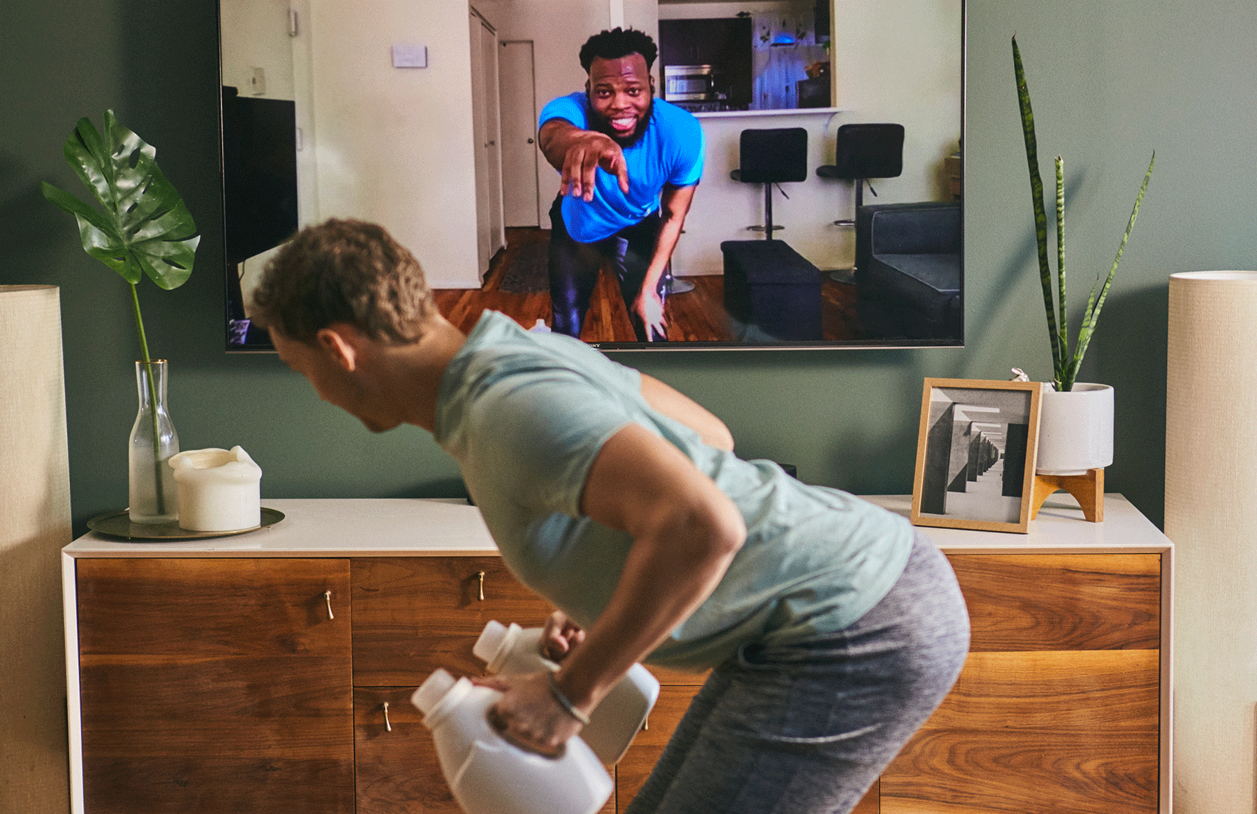 male client working out at home with male personal trainer coaching him virtually