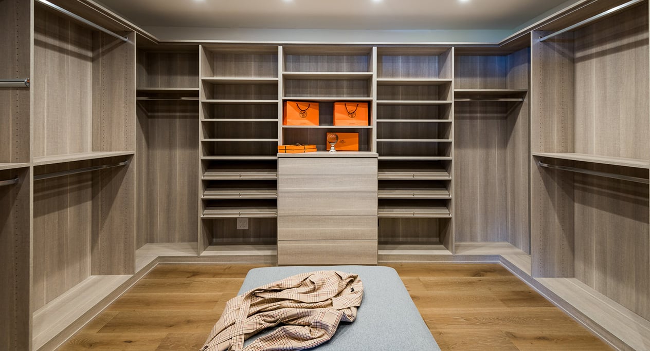 Wood Grain Finish Walk In Closet | California Closets Pasadena Spacious walk-in closet with shoe shelves, built-in drawers, and hanging space in medium wood by California Closets Pasadena.