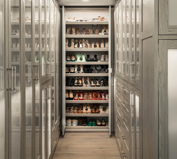 Sleek Custom Walk-in Closet gray full room wardrobe, closed cabinetry with shaker doors with frosted glass inserts, LED lighting throughout closet, mirrored doors in the middle of the closet with shoe storage behind Upper West Side New York