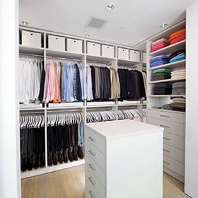 Three ways to keep your closet organized Custom white walk in closet with shelving and dresser in center by California Closets Missoula & Western Montana.