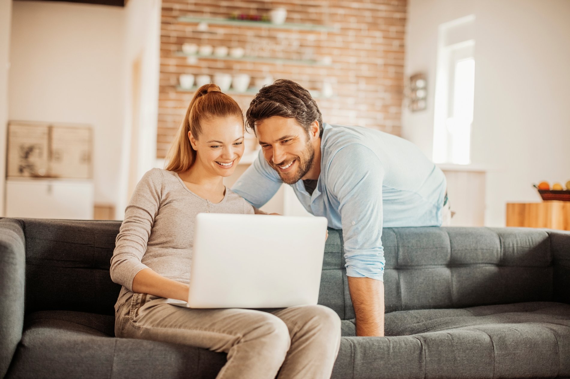 Couple on living room couch looking at laptop