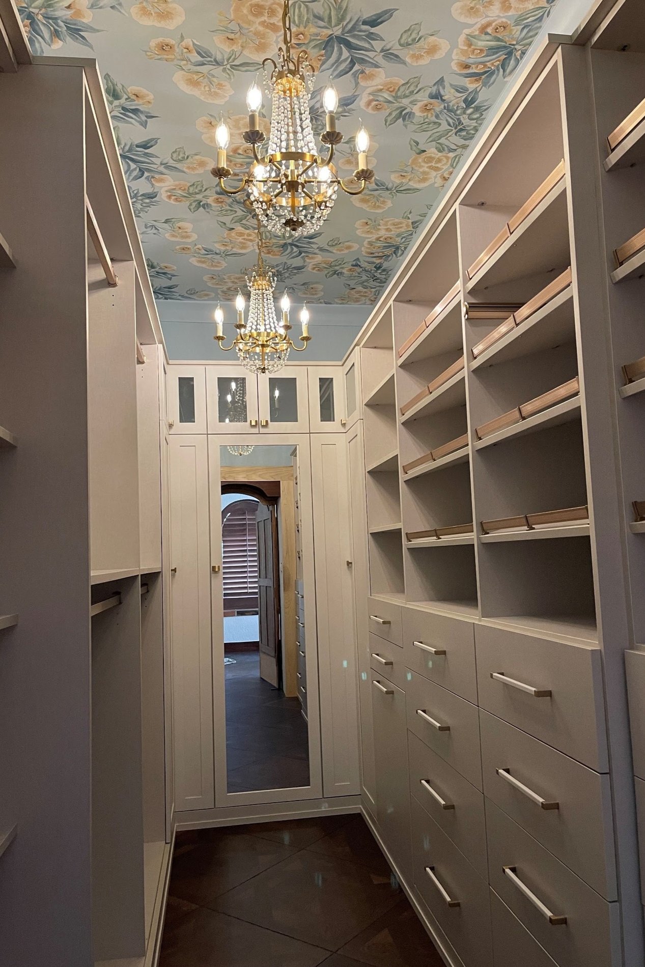 Narrow Walk-In Closet Narrow custom walk-in closet with floor-to-ceiling shelving, built-in drawers, wardrobe storage, and decorative ceiling details.
