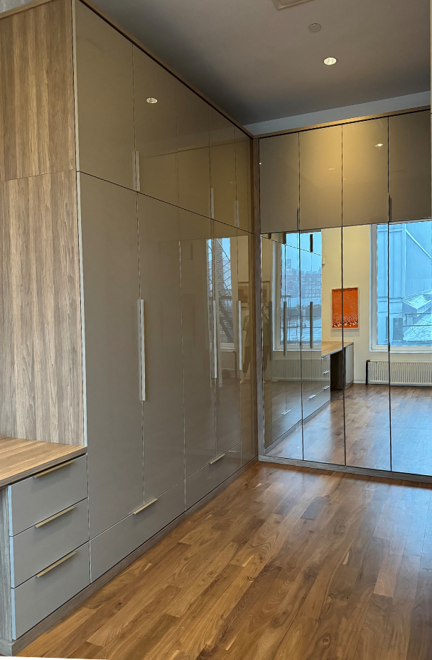 Modern New York City Walk-in Closet California Closets NYC walk-in closet two-tone closet with natural wood and high gloss gray on door fronts, as well as mirrored doors. Closed storage with various hanging and shelving areas for ample storage space.