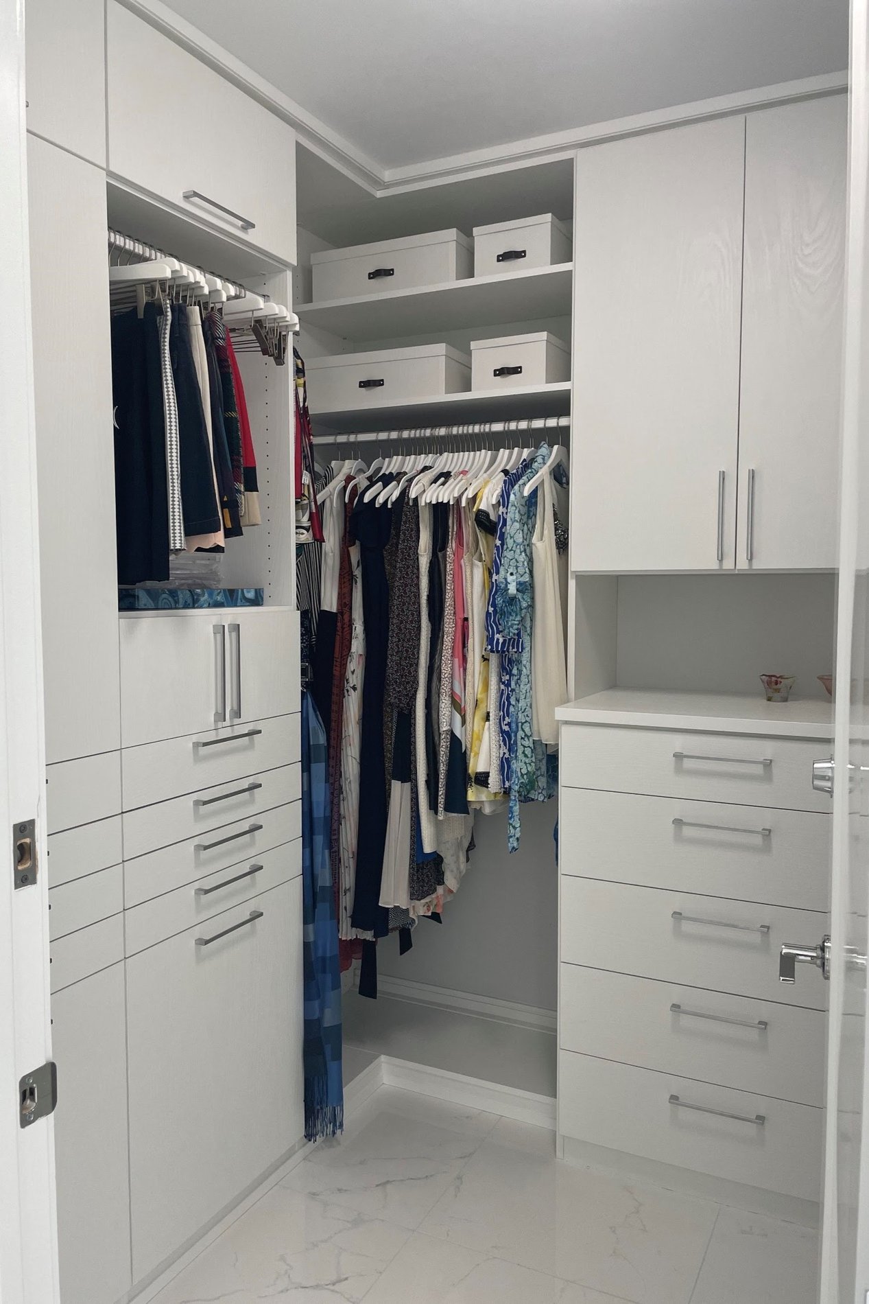 Walk-In Closet White custom walk-in closet with floor-to-ceiling cabinetry, hanging storage, built-in drawers, shelving, and wardrobe organization.