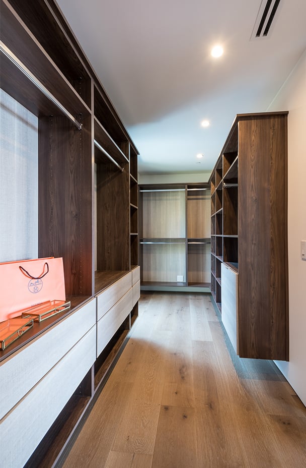 Large Walk In Closet Design | California Closets Pasadena Walk in closet with floating cabinets and extra drawer space in a dark wood grain finish by California Closets Pasadena